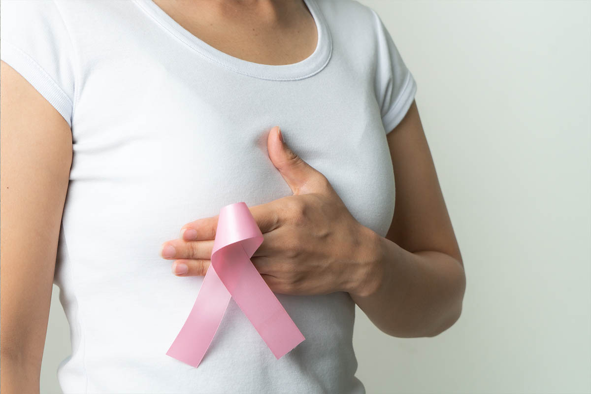 Un fiocchetto rosa, simbolo di prevenzione di tumore al seno, tenuto in mano da una donna