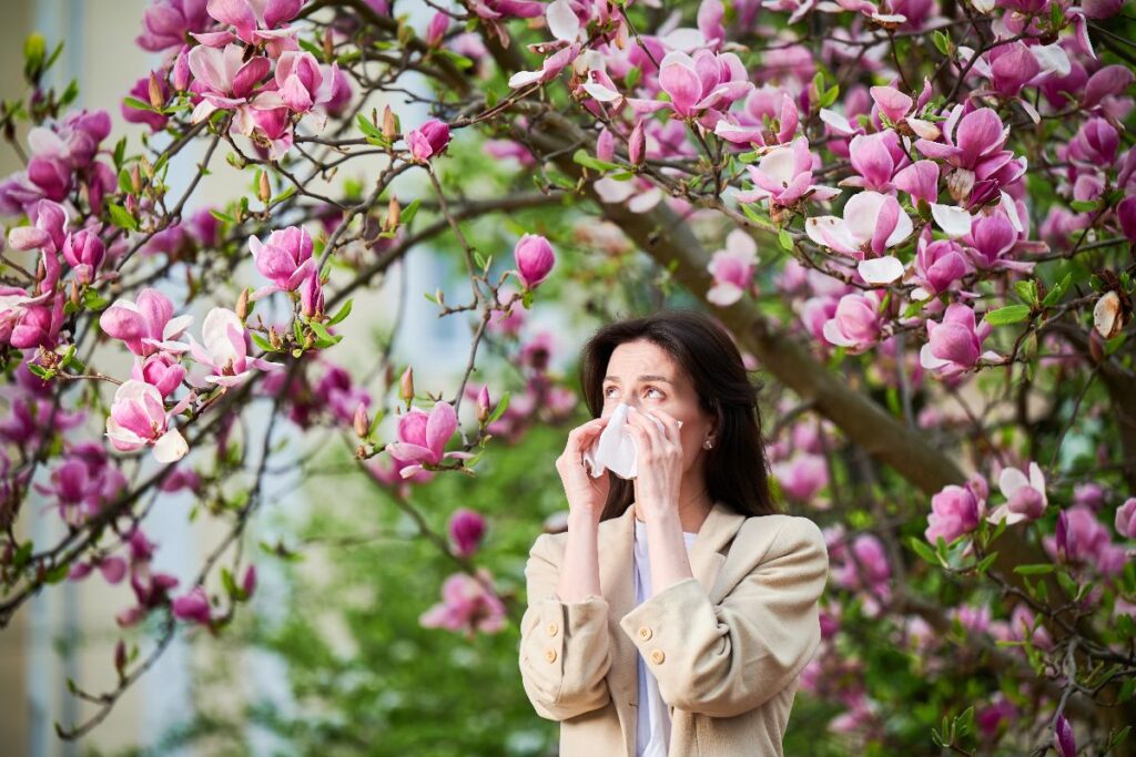Giovane donna colta da uno starnuto dovuto ai pollini primaverili.