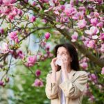 Giovane donna colta da uno starnuto dovuto ai pollini primaverili.
