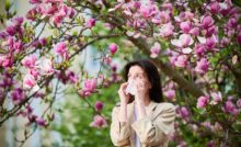 Giovane donna colta da uno starnuto dovuto ai pollini primaverili.