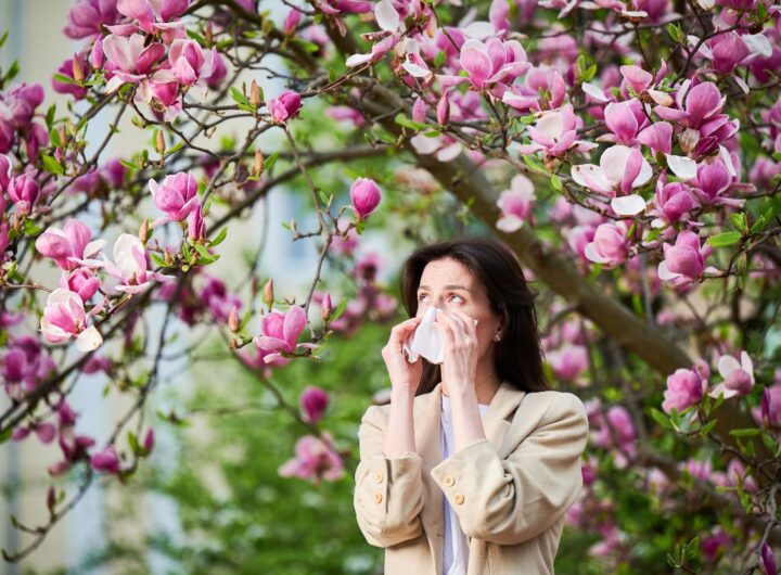Giovane donna colta da uno starnuto dovuto ai pollini primaverili.