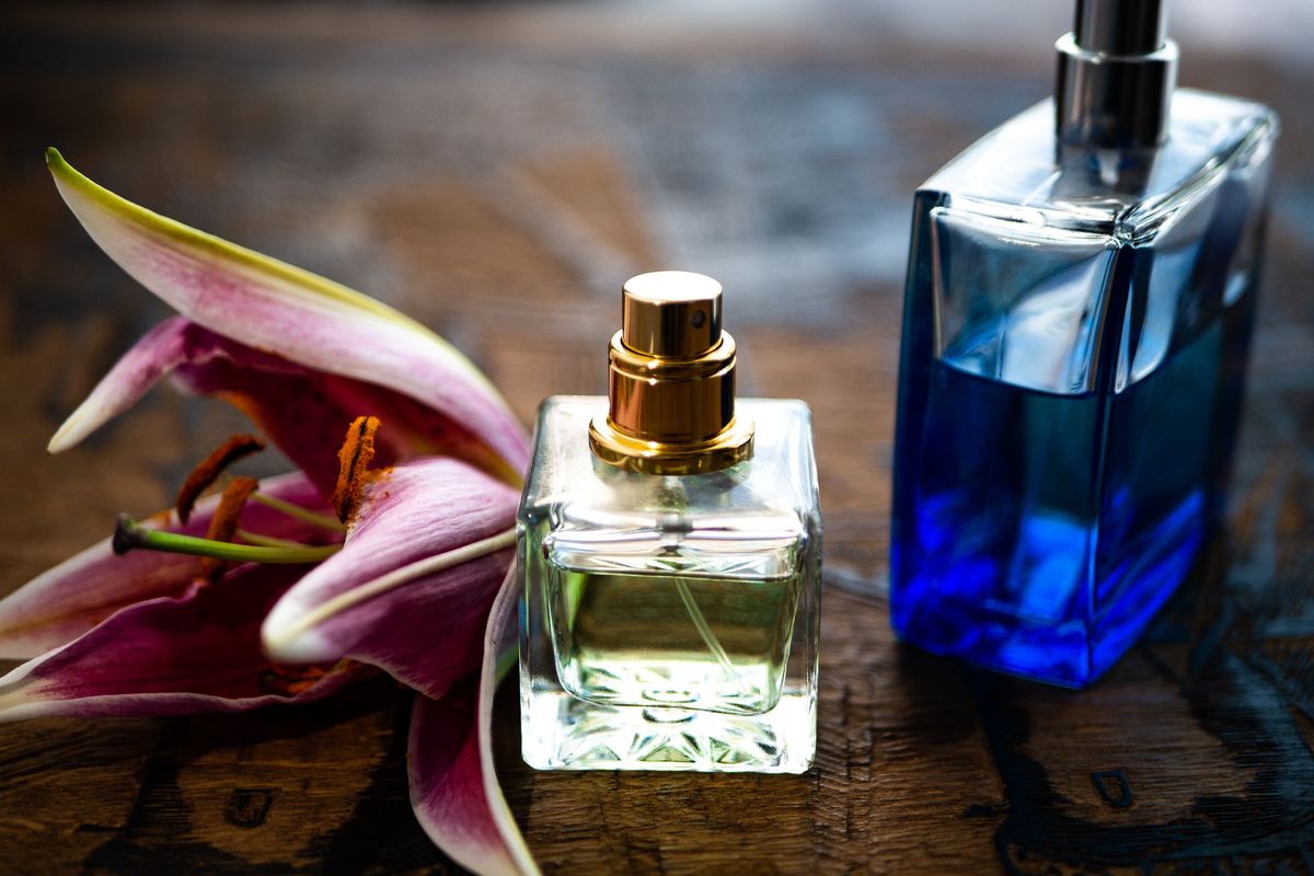 Confezioni di profumo disposte vicino a un fiore