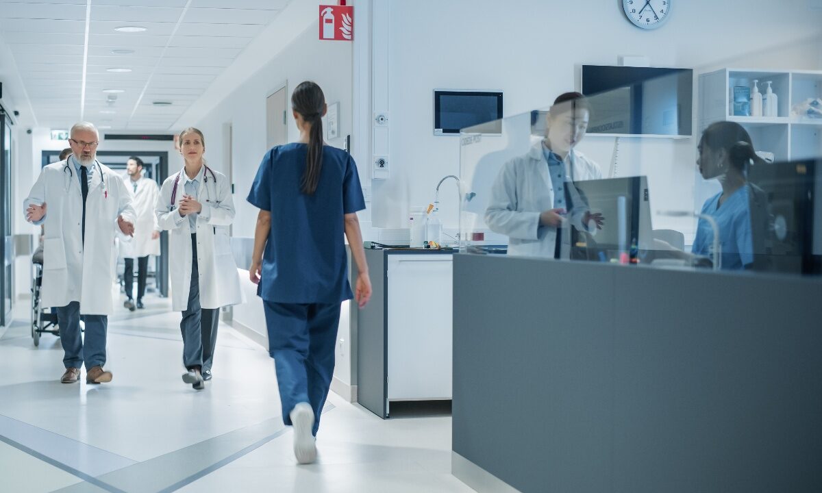 Medici e infermieri ripresi mentre camminano lungo un corridoio d'ospedale.